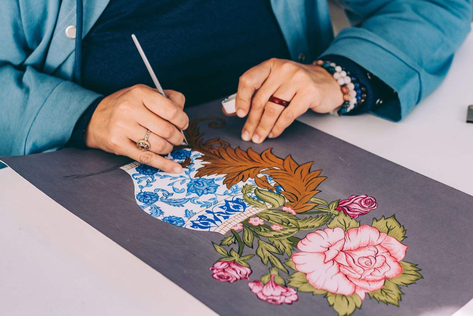 Un artiste dessine méticuleusement des motifs floraux sur une toile, mettant en valeur les compétences artisanales tradi